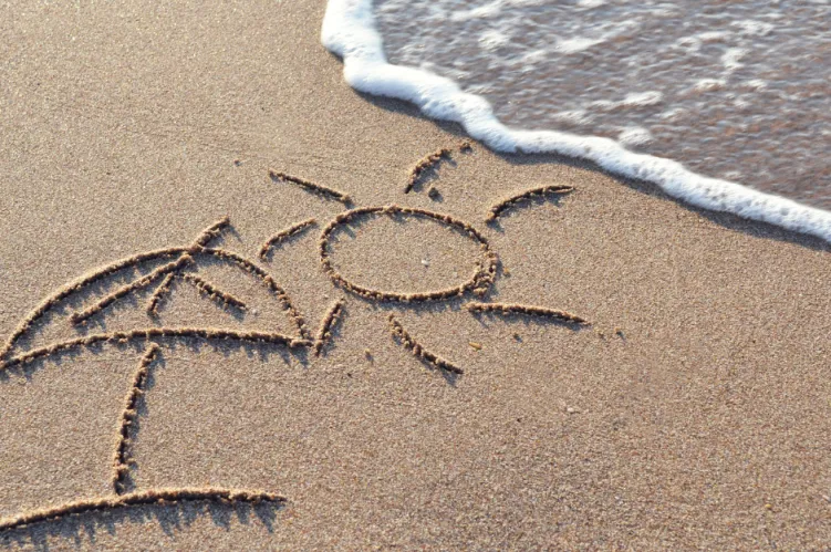 plaża, na piasku odrysowany parasol i słońce 