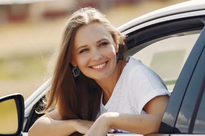 uśmiechnięta kobieta wystawi głowę przez okno